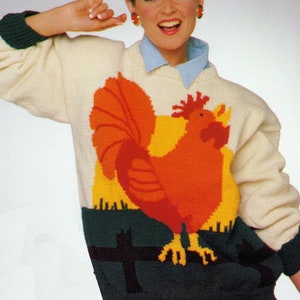 Puede incluir: Patrón de tejido para un suéter blanco con un diseño de gallo colorido. El suéter tiene un cuello azul y un fondo azul y verde con una valla negra. El patrón se llama "Io" y es una descarga PDF.