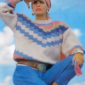 Könnte beinhalten: Eine Frau trägt ein rosa Stirnband und einen blau-weiß gestreiften Pullover mit einem rosa, blauen und beigefarbenen Muster. Sie trägt eine blaue Jeans und einen braunen Gürtel mit einer silbernen Schnalle. Der Text "Io" befindet sich in der oberen rechten Ecke des Bildes. Der Text "PDF Pattern" befindet sich am unteren Rand des Bildes.