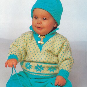 Pode incluir: Um conjunto de malha para bebé em amarelo e azul turquesa com um chapéu a condizer em azul turquesa. O conjunto apresenta um padrão de floco de neve e o chapéu tem um pompom no topo. O texto "PDF Pattern" está impresso na parte inferior da imagem.