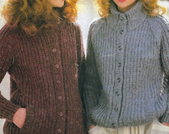 May include: Two women wearing knitted cardigans with button closures. The cardigan on the left is a deep burgundy color and the cardigan on the right is a light blue color. Both women are wearing hats.