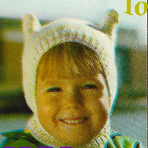 Könnte beinhalten: Eine weiße Strickmütze mit Ohrenklappen, die einem Comic-Charakter ähnelt, getragen von einem Kind mit einem lächelnden Gesicht. Die Mütze hat ein strukturiertes Strickmuster und ist im Stil einer Kapuze. Das Bild enthält den Text "PDF Pattern".