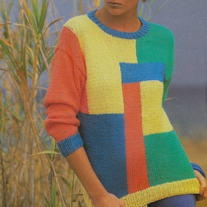 Può includere: Un maglione colorato con un motivo geometrico. Il maglione presenta un design patchwork con blocchi gialli, verdi, blu, arancioni e rossi. Le maniche e lo scollo sono rifiniti in blu. Il maglione è realizzato in materiale a maglia.