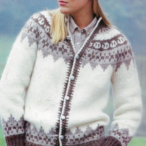 Peut inclure: Cardigan crème avec un motif géométrique dans les tons marron et gris. Le pull a une fermeture boutonnée sur le devant et des poignets côtelés. Le motif présente un motif répétitif autour de l'empiècement et des poignets.