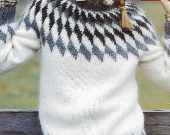 May include: A white, gray, and black patterned sweater. The sweater features a diamond design around the yoke and hem. The long-sleeved sweater is made of a soft, textured material. The model is wearing a plaid shirt underneath.