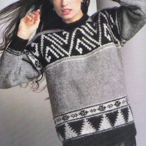 May include: A black, white, and gray knitted sweater with a geometric pattern. The sweater has a crew neck and long sleeves. The model is wearing the sweater with a black skirt.