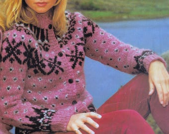 May include: A pink cardigan with a black geometric pattern and small white dots. The button-down sweater has long sleeves and a high collar. The person in the image is wearing red pants.