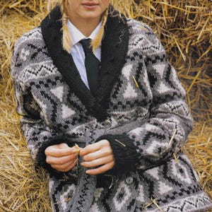 Könnte beinhalten: Ein grau, schwarz und weiß gemusterter Cardigan mit Schalkragen und Knopfverschluss. Der Pullover hat ein geometrisches Design und schwarze Manschetten. Die Person trägt ein weißes Hemd und eine schwarze Krawatte.