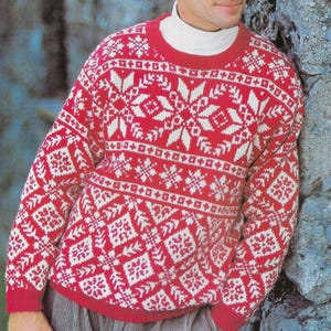 May include: A long-sleeved crew neck jumper featuring a vibrant red and white geometric pattern with repeating snowflake and diamond motifs. The garment is worn over a plain white mock neck base layer, showcasing a classic knit construction.