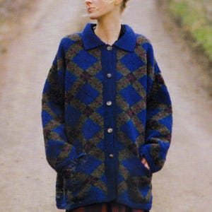 May include: A blue cardigan with a diamond pattern in blue, green, and burgundy. The long-sleeved sweater has a collared neckline and two front pockets. The person is wearing the cardigan outdoors. The cardigan is buttoned up.