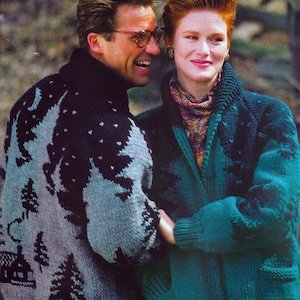 May include: A couple wearing matching knit jumpers with a forest scene design. The jumpers are teal and grey with black accents. The man is wearing a teal jumper and the woman is wearing a grey jumper. The jumpers have a forest scene design with trees, mountains, and stars.