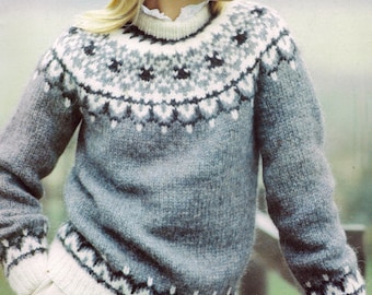 May include: A gray knit sweater with a patterned yoke in white, gray, and black. The sweater has a ribbed collar and cuffs. The model is wearing a white collared shirt underneath. The sweater is a classic, cozy style.
