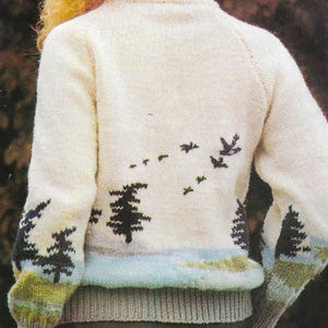 May include: A white knitted sweater with a black and white design of trees and birds. The sweater has a crew neck and long sleeves.