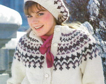 May include: A woman wearing a white knit cardigan and matching beret with a geometric pattern in shades of purple. A burgundy scarf is worn around the neck. The cardigan has white buttons.