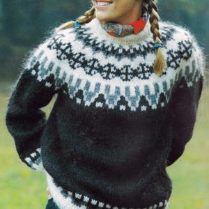Könnte beinhalten: Ein gestrickter Pullover in Schwarz, Weiß und Grau mit hohem Kragen. Der obere Teil des Pullovers hat ein geometrisches Muster, während der untere Teil einfarbig schwarz ist. Die Ärmel sind lang und der Stil ist warm und gemütlich.