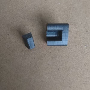 May include: Two small, black, plastic corner pieces. The pieces are designed to be used in a corner of a project.