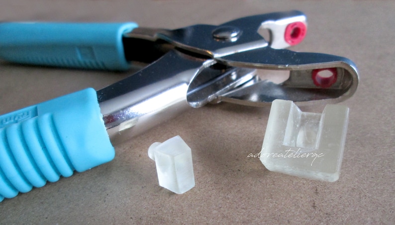 May include: A silver metal punch tool with blue rubber handles and two clear plastic punch inserts.