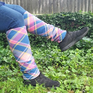 Puede incluir: Un par de polainas de color azul, rosa y amarillo a cuadros. Las polainas se llevan en las piernas de una persona y están hechas de un material suave y peludo.