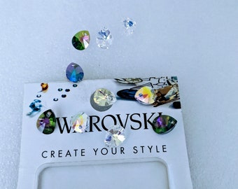 May include: A selection of iridescent Swarovski crystals in different shapes, such as teardrops and faceted rounds. The crystals are displayed on a white card with the brand name and the slogan "CREATE YOUR STYLE".