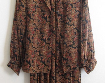 May include: A black and brown paisley print blouse and skirt set. The set has a button-up front and long sleeves.