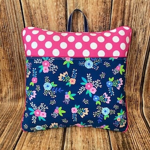 May include: A blue and pink pillow with a floral pattern and white polka dots. The pillow has a zipper closure and a loop for hanging.