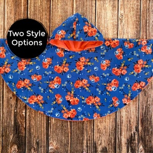 May include: A blue hooded poncho with a floral print and a coral lining. The poncho is made of soft fleece and is perfect for keeping warm on chilly days.