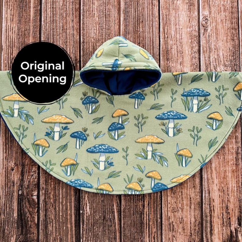 May include: A green fleece poncho with a hood, featuring a pattern of blue and yellow mushrooms and foliage. The hood is lined with dark blue fabric. The poncho is designed with an opening for the head.