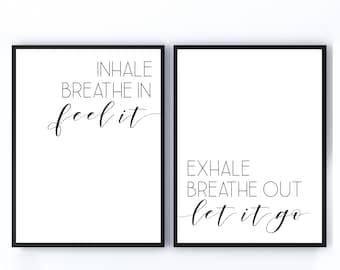 May include: Two black framed prints with white backgrounds and black text. The left print says "INHALE BREATHE IN feel it". The right print says "EXHALE BREATHE OUT let it go".