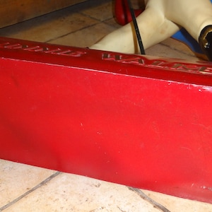 May include: Red base with the words "Jubilee Walker" printed on it. The base is made of a hard material and has a slightly worn surface.