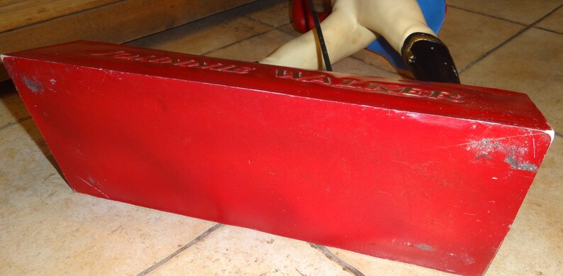 May include: Red base with the words "Jubilee Walker" printed on it. The base is made of a hard material and has a slightly worn surface.