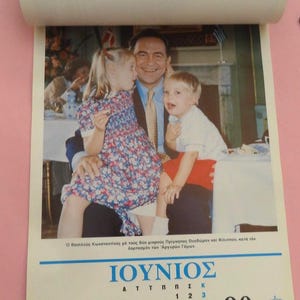 May include: A calendar page featuring a photograph of a man with two children. The calendar displays the month of June, with the date 19 highlighted. The image includes text in Greek.