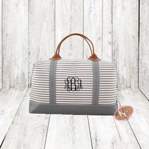 May include: A grey and white striped canvas travel bag with brown leather handles and a monogrammed initial "B".