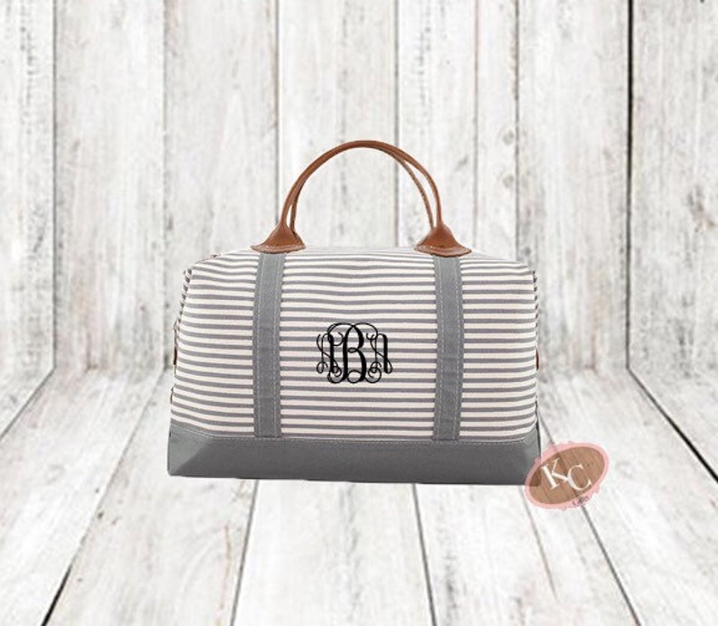 May include: A grey and white striped canvas travel bag with brown leather handles and a monogrammed initial "B".