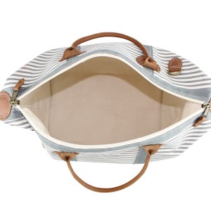 May include: A striped canvas travel bag with brown leather handles and accents. The bag is open and the interior is visible.