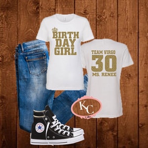 May include: White t-shirt with gold glitter text that says "Birthday Girl" with a crown above the text. A second white t-shirt with gold glitter text that says "Team Virgo 30 Ms. Renee". Blue jeans and black high-top sneakers.