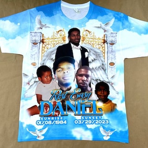 May include: A blue and white t-shirt with a photo collage of four people. The shirt has a white background with a blue sky and clouds. The photo collage includes a man in a suit, a man in a cap, a young boy, and a young girl. The shirt also has the text "Rest Easy Daniel" and the dates "01/08/1984" and "03/29/2023".