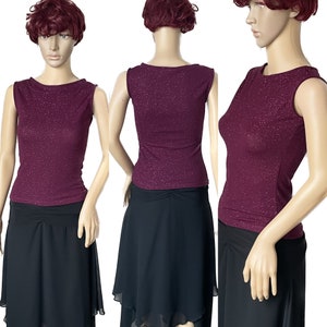 May include: A sleeveless burgundy top with a sparkly texture, paired with a black skirt. The skirt has a gathered waist and a layered, asymmetrical hem.