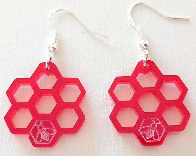 Honeycomb earrings, laser cut from semi-transparent red acrylic, with a little bee.