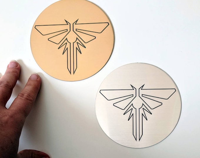 The Last of Us sticker, metallic silver and gold. Fireflies symbol from TLOU and TLOU2, laser engraved. Great for laptops!