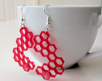 Honeycomb earrings, laser cut from semi-transparent red acrylic, with a little bee, laser engraved
