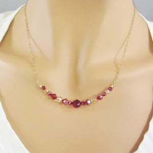 May include: A gold chain necklace with a delicate row of red and gold crystal beads.