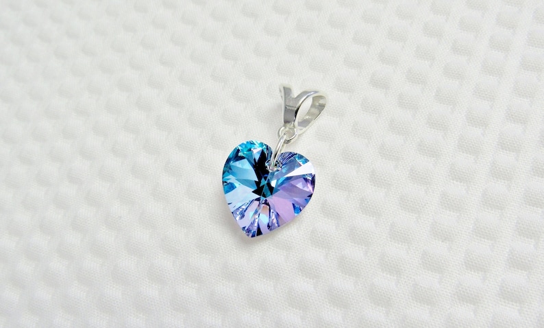 May include: A silver heart-shaped pendant with a blue and purple crystal.