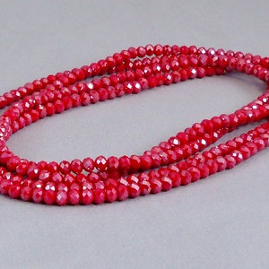 May include: A red crystal bead necklace with a silver-toned bead accent. The necklace is layered and has a shiny finish.