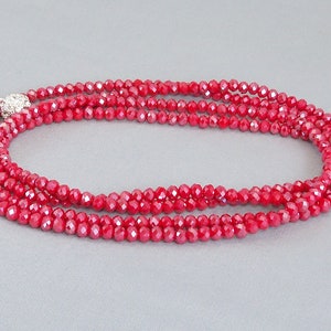 May include: A red crystal necklace with a silver clasp. The necklace is made of small, faceted beads and is layered for a more dramatic look.