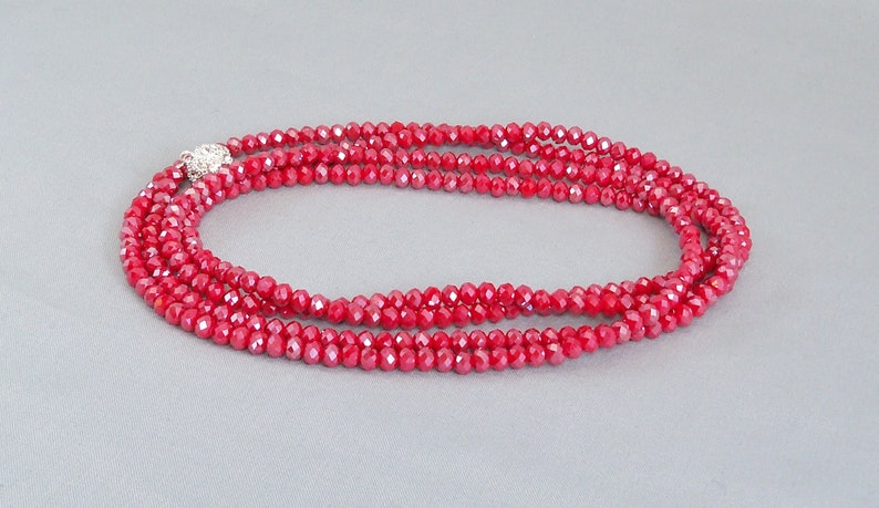 May include: A red crystal necklace with a silver clasp. The necklace is made of small, faceted beads and is layered for a more dramatic look.