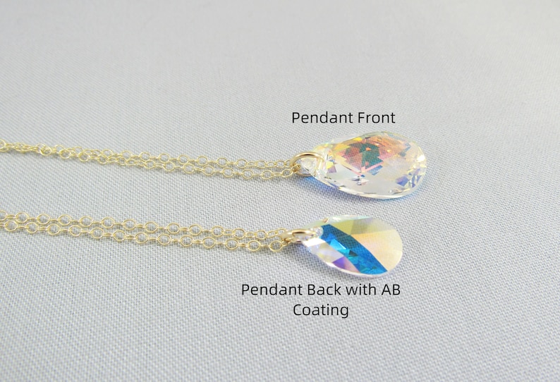 Pu&ograve; includere: Una collana con catena dorata con un ciondolo di cristallo a forma di lacrima. Il ciondolo ha un davanti trasparente e un retro iridescente arcobaleno.