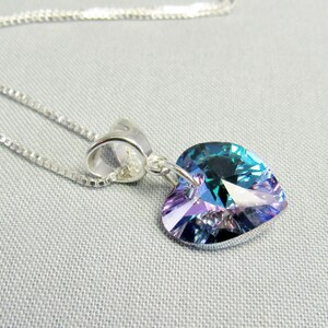 May include: A silver necklace with a heart-shaped pendant. The pendant is a vibrant mix of blue, green, and purple hues. The chain is a delicate silver box chain, and the pendant is attached with a silver bail.