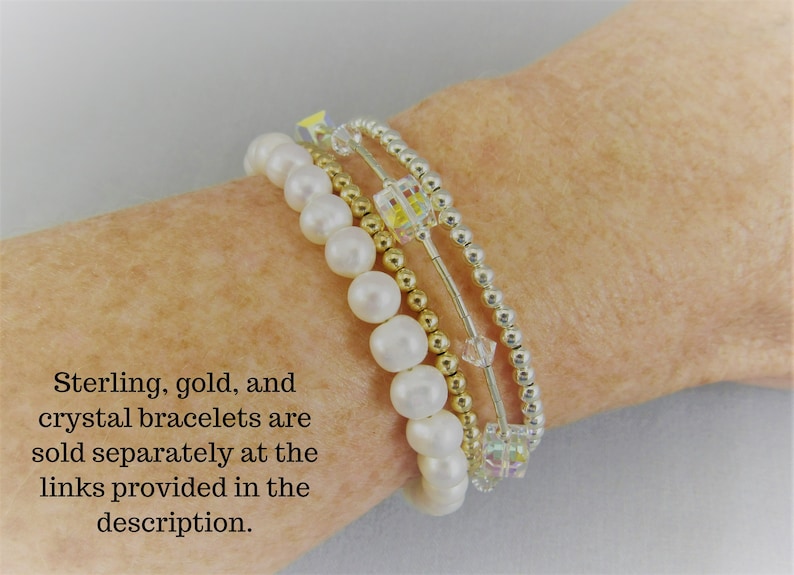 May include: Four bracelets stacked on each other. The top bracelet is silver with small round beads. The second bracelet is gold with small round beads. The third bracelet is silver with small round beads and clear crystal cube beads. The bottom bracelet is white with 6mm round beads. The text on the image reads: 'Sterling, gold, and crystal bracelets are sold separately at the links provided in the description.'