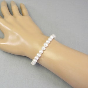 May include: A white pearl bracelet with a simple design. The bracelet is made of round, white pearls that are strung together.