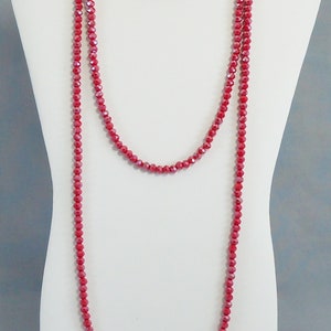 May include: A long, layered necklace made of red faceted beads. The necklace is displayed on a white mannequin bust.