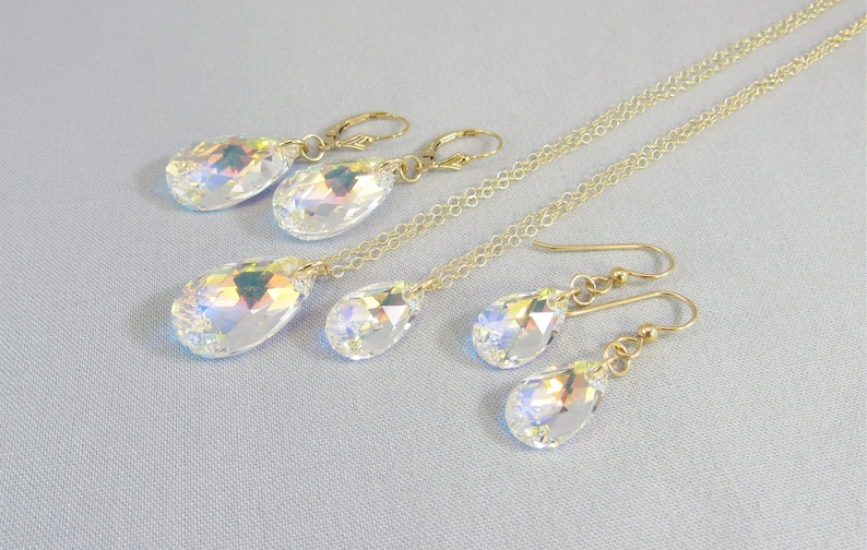 Pu&ograve; includere: Un set di collana e orecchini a catena dorata con ciondoli di cristallo a forma di lacrima iridescenti.